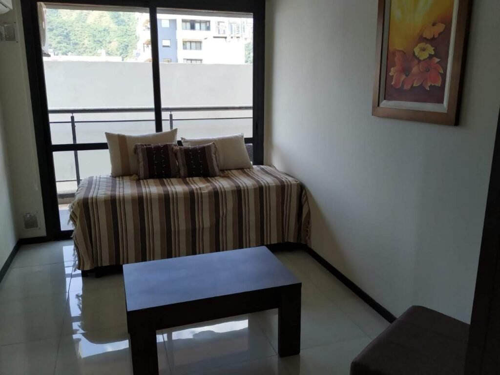 Living con sofá cama y salida al balcón, en un departamento céntrico de Villa Carlos Paz